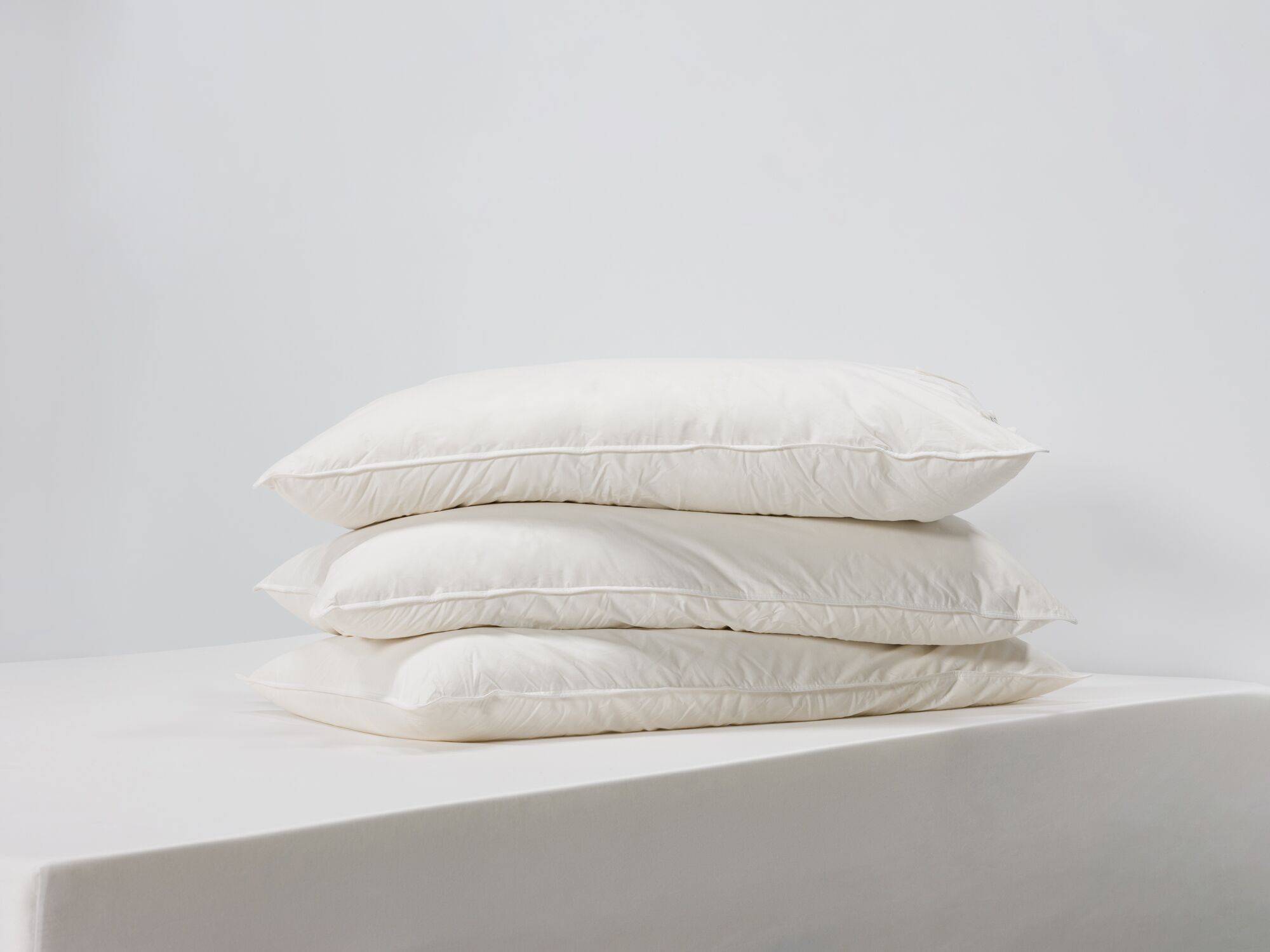 Side view of three king size feather pillows stacked